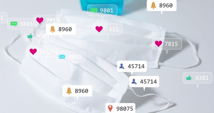 Displaying two pleated face masks lying on tabletop in studio, with floating social media icons