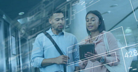 Colleagues reviewing charts on tablet in corporate corridor, with digital interface overlay