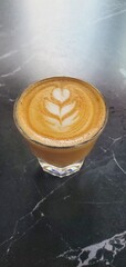 glass of italian cortado coffee sitting on a black marble cafe table