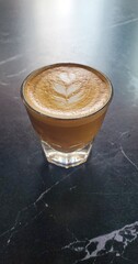 glass of italian cortado coffee sitting on a black marble cafe table