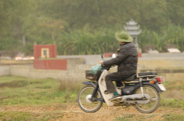 Fototapeta premium Vietnamese man on motorcycle. Van Long Wetland Nature Reserve. Gia Vien District. Ninh Binh Province. Vietnam.