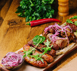 Grilled meat platter with fresh herbs and toppings served on a wooden board