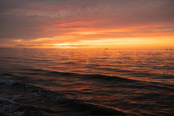 Obraz premium Asnelles-Sur-Mer, France - 08 08 2025: Panoramic view of the sea, waves, artificial port and the colorful cloudy sky at sunset along the jetty