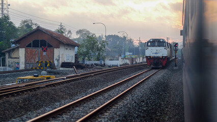 Indonesian Train Passing Through Railway Tracks at Sunset in a Small Town
