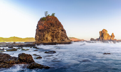 Dramatic Seaside Landscape with Long Exposure, Smooth Wave, Rocks and Sunset in Yogyakarta, Indonesia