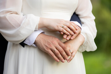 Fototapeta premium Groom embracing bride – close-up of hands and wedding rings