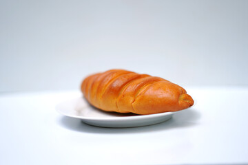 Golden Brown Bakery Bun Served on Dish with White Background.