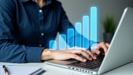 Hands type on a laptop, with glowing blue bar graphs rising, representing data growth or business analytics.