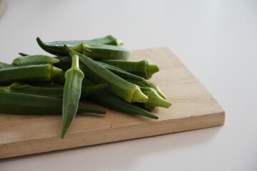 Several fresh okra pods on wooden surface, close-up.