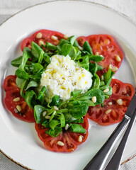 Enjoy a refreshing tomato salad with greens and creamy soft