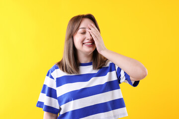 Attractive woman laughing on yellow background. Positive emotion