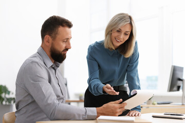 Fototapeta premium Smiling business partners working with documents at table in office