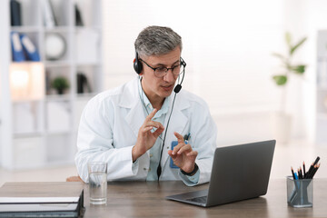 Obraz premium Telemedicine. Doctor having video call with patient via laptop indoors