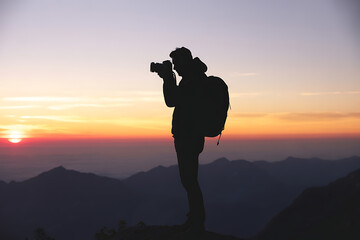 Silhouette of Photographer at Sunrise Over Mountain Range