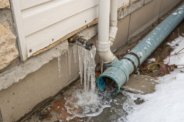 a frozen, burst water pipe in a north american home, with icicles forming