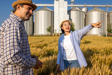  Two Silo Workers Standing in Wheat Field Discussing Future Tasks