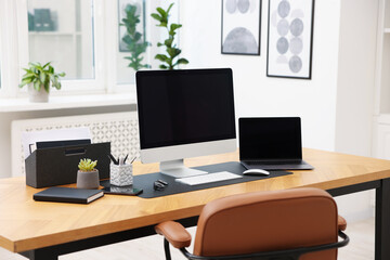 Stylish workplace with modern computer, laptop and stationery on wooden desk indoors