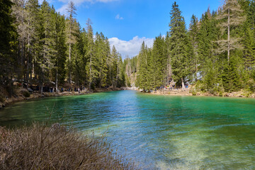 March 2025: view of Braies Lake in winter, with a frozen surface marked by trails, surrounded by snow covered cliffs, rugged rocks, and evergreen trees.a