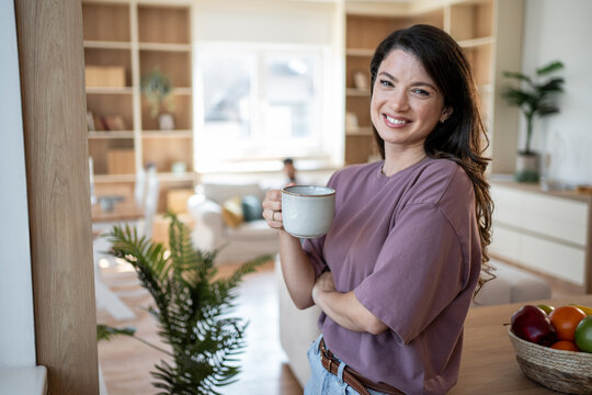 Smiling woman enjoying morning coffee in modern apartment