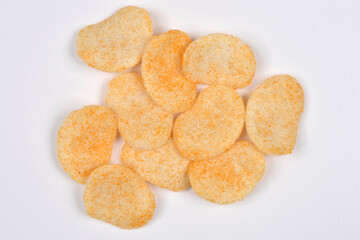 A pile of crunchy oval wheat and oat snacks, sprinkled with orange powder, arranged on a white...