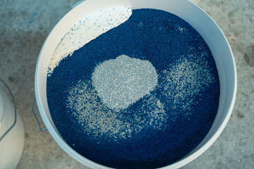 Production of decorative plaster at the factory. Materials for repair and decoration. Closeup of blue decorative plaster mixture in a bowl showcasing texture and contrast.