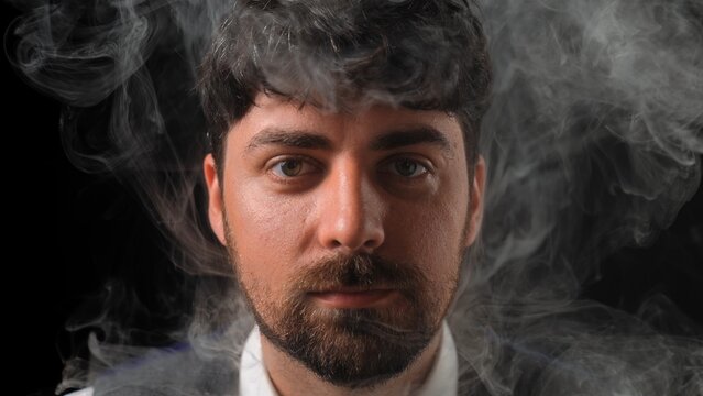 Male businessman on black background in white smoke clouds