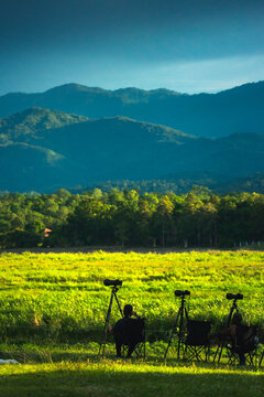 Birdwatchers with Telescopes in Green Field and Mountain View