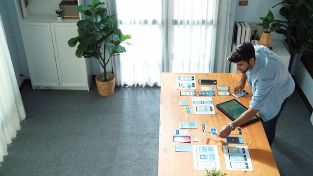 Top view of smart businessman holding tablet while looking at UX or UI design document at meeting table while analyzing data.Skilled manager choose idea or designing prototype or program. Convocation.