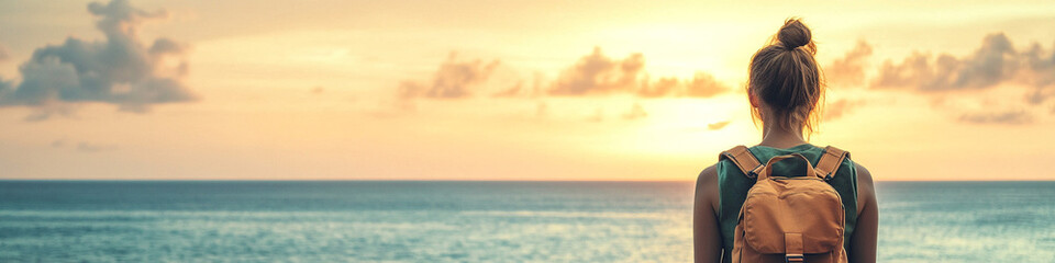 Solo female traveler with backpack watching the sea in warm dusk