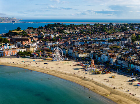 People enjoying the sandy beach and funfair at Weymouth on the Jurassic Coast.