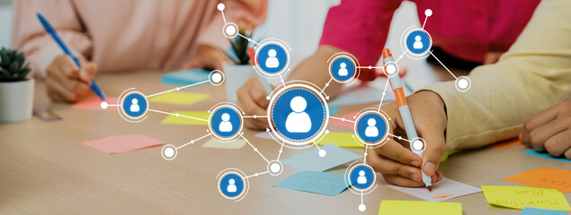 Engaging in collaborative networking, team members share notes and ideas in a modern workspace,...