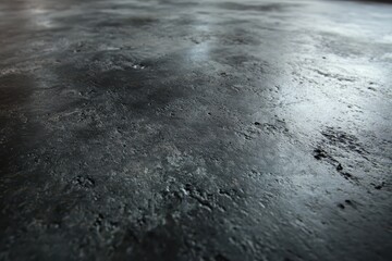 Realistic close-up view of a dark concrete floor with a textured surface highlighting subtle variations in color and pattern under soft light conditions