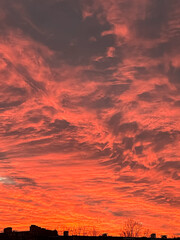 Vibrant sunset sky filled with dramatic clouds in shades of orange and pink, creating a stunning natural display of color and texture