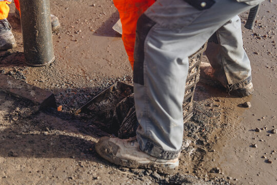 Roadworkers opened clogged road gully and cleaning it from debris and dirt using vac-ex and power jet wash