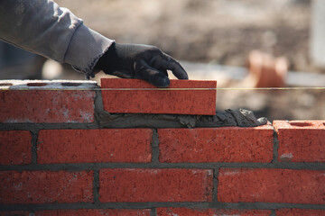 Close-up of skilled bricklayer working on construction site laying bricks for wall construction