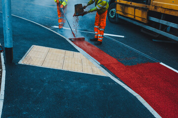 Road construction activity with roadworker applying hot melted white paint for traffic lines demarcation on new road surface