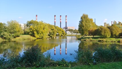 Trees grow on the grassy banks of the river and are reflected in the water. There are reeds in the...