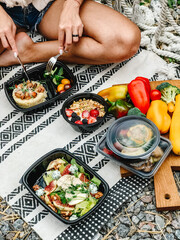 Picnic with healthy meals, fruits and ready food containers outdoors.
