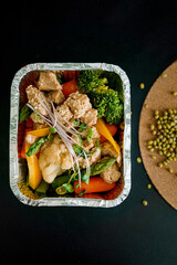 Takeaway healthy food in aluminum foil containers with vegetables and grains.