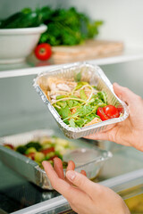 Takeaway healthy food in aluminum foil containers with vegetables and grains.