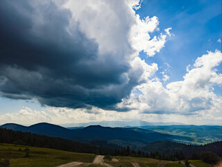 A stunning view of a lush mountain range under a bright blue sky with rolling clouds, perfect for travel, nature, and outdoor adventure promotions