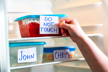 Sarcastic sticker warnings Not Your Food and Do Not Touch on lunch boxes in shared office refrigerator. Office life.