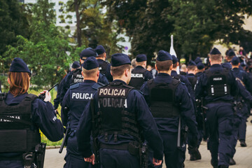 Group of Polish police officers in navy uniforms and tactical gear walking together during a demonstration in Warsaw, ensuring public order and safety. © Yurii Zymovin