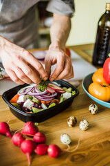 Hands cutting onion and radish for fresh vegetable salad.
