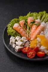 Bowl with shrimps, seafood, rice, oranges, tomatoes with sauce. Bowl with prawns