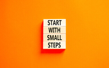 Start with small steps symbol. Concept words phrase Start with small steps on beautiful wooden blocks. Beautiful orange paper background. Business Start with small steps concept. Copy space.