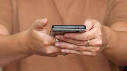 close up woman hand holding phone. female hand using phone brown skin. close-up of a woman's hand holding a phone