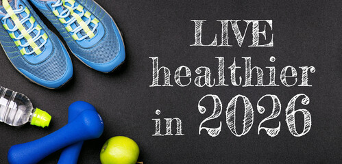 New year 2026 resolutions healthy lifestyle and sport. Be healthy in 2026. Motivation sport goals 2026 with sport equipment shoes, dumbbells, fruit and water bottle on black background