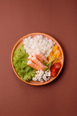 Bowl with shrimps, seafood, rice, oranges, tomatoes with sauce. Bowl with prawns