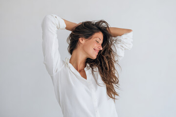 Fototapeta premium young woman with long casually tousled hair smiles gently with her head bowed after stretch
